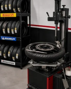 Máquina de cambio de neumáticos con rueda de moto y estantería con neumáticos de marca